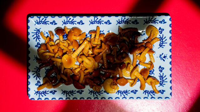 setas en un plato alargado de cer&aacute;mica, pholiota nameko, com&uacute;nmente conocido como nameko, hongo basidiomiceto de la familia Strophariaceae. Su seta es peque&ntilde;a, con un sombrero de color &aacute;mbar 