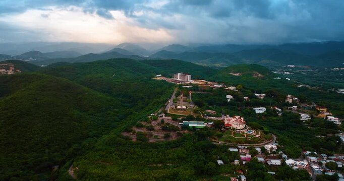 Flying closer to the Watchman Cross on the verdant mountain hill. Landmark of Ponce, Puerto Rico. Dramatic dark clouds over the rocks at backdrop.