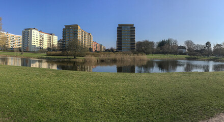 Obraz premium Sunny urban park with pond and residential apartment buildings in Malmö Sweden