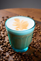  A cup of cappuccino coffee with a foam pattern, top view. Coffee beans are scattered around it.                              