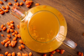 Sea buckthorn tea in a teapot stands on a wooden table, top view                               