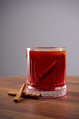 A drink with cinnamon in a transparent glass stands on a wooden table                               