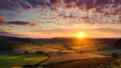 Vibrant sunset casting golden light over a picturesque rolling landscape of fields and hills under a dramatic cloudy…