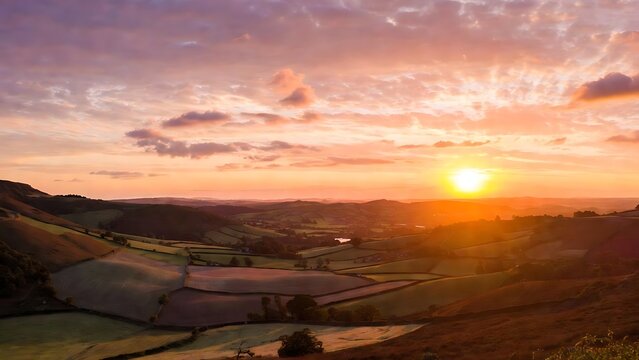 Vibrant sunset casting a warm golden glow over a picturesque rolling landscape with rural fields and distant