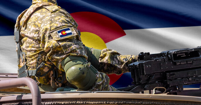 Colorado US state flag with soldier at machine gun turret in front of it.