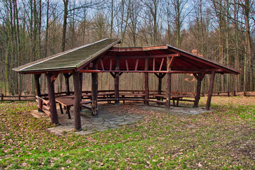 Rustykalna drewniana altana piknikowa w parku ze stołami i ławkami - rezerwat przyrody "Ostrzyca Proboszczowicka". © Pol Badger