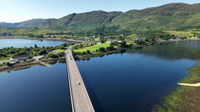 Aerial view of Dornie bridge Scotland over loch Duich toward mountains on a bright sunny day