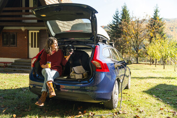 Woman with her dog sitts into trunk of electric car