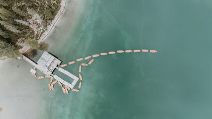 Vue aérienne de barques en bois amarrées sur les eaux turquoise du lac de Braies, Dolomites