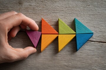 Hand placing colorful triangular puzzle pieces on a wooden surface