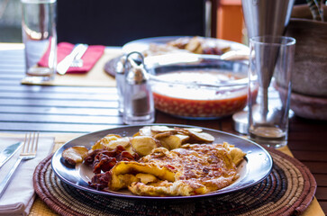 Breakfast table setting with eggs, bacon, potatoes and baked beans on rattan placemat, selective focus