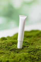 Tubo blanco de crema cosm&eacute;tica sobre musgo, Envase de crema hidratante sobre fondo de musgo verde, Mockup para marca de cosm&eacute;tica natural, Envase para cosm&eacute;tica vegana con packaging sostenible