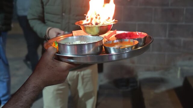 A devotee making offerings in aarti thali.