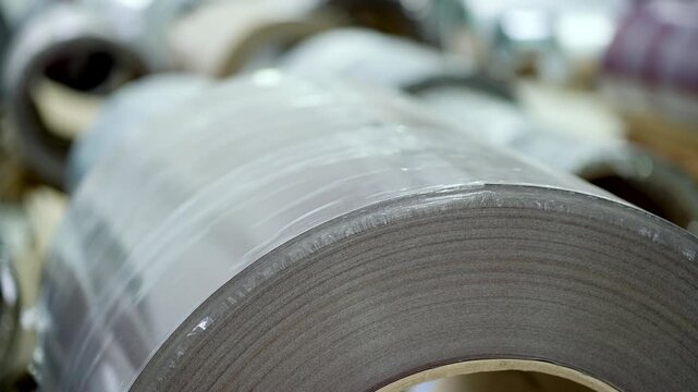 Many metal coils for roofing sheet production are stored and kept in the factory warehouse. large metal coil for roofing sheet production, handling heavy industrial