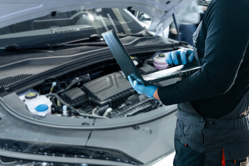 Serviceman with laptop checks car software in car service