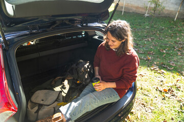Woman with her dog sitts into trunk of electric car