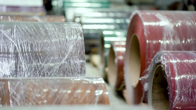 Many metal coils for roofing sheet production are stored and kept in the factory warehouse. large metal coil for roofing sheet production, handling heavy industrial