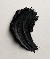 Black charcoal smudge creating abstract cosmetic brushstroke texture