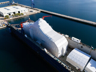 Aerial view of a luxury yacht refit, repair, service and maintenance in a floating dock at a marina.
