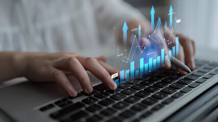 Close-up view of hands typing on a laptop with an overlay of digital graphs and data, representing business growth, analysis, and the power of technology in modern workplaces. Scalp