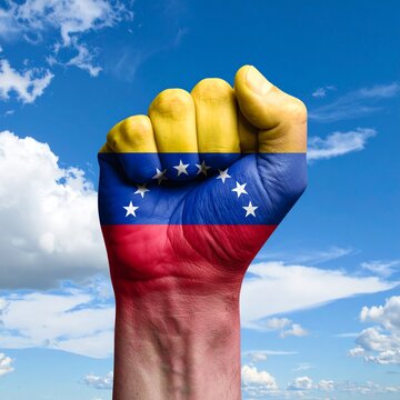 Un pu&ntilde;o alzado con los colores de venzuela, por detras un cielo celeste