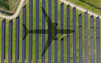 Aerial view of an airplane shadow cast across a solar panel field. Aviation uses renewable energy, modern technology and the transition toward a sustainable future.