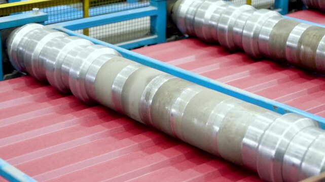 A rolling machine in the factory produces and presses metal sheets with high precision for roofing sheet manufacturing. roofing production processes. Roof sheet factory. Steel roofing forming machine.