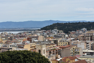 Fototapeta premium Aerial view of Cagliari, Sardinia, Italy. Colorful buildings and greenery contrast with distant mountains. Holidays in Sardegna. Travel to Italy. Travel and tourism concept. 