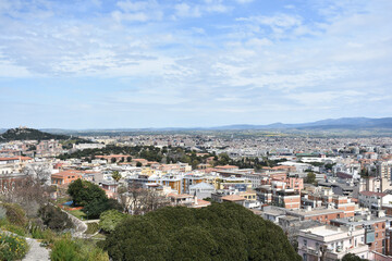 Fototapeta premium Aerial view of Cagliari, Sardinia, Italy. Colorful buildings and greenery contrast with distant mountains. Holidays in Sardegna. Travel to Italy. Travel and tourism concept. 