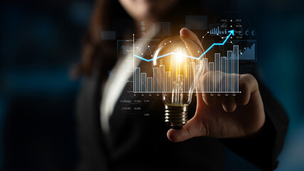 A focused business professional holds a glowing light bulb, surrounded by digital graphs and charts, symbolizing innovation and strategic growth in the financial sector. Scalp