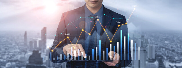 A businessman stands in an urban environment analyzing financial data on a tablet. Digital graphs and charts display trends and insights, symbolizing modern business analytics. Scalp
