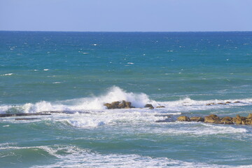 Seascape with waves crashing on the rocks in a sunny day