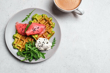 Healthy breakfast with green spinach vegetable waffles, salmon, cream cheese and arugula