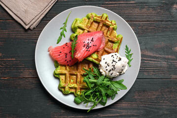 Healthy breakfast with green spinach waffles, salmon, cream cheese and arugula