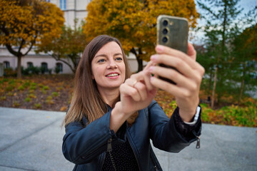 Woman taking photo with smartphone outdoors in autumn