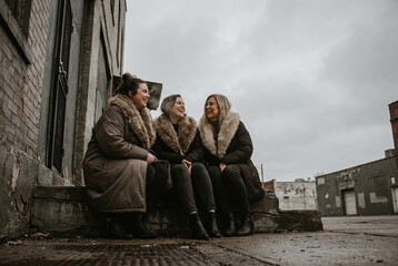 Three Happy Women Laughing on Urban Steps on an Overcast Day