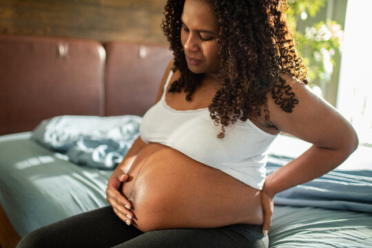 Adult pregnant woman in discomfort with back pain at home