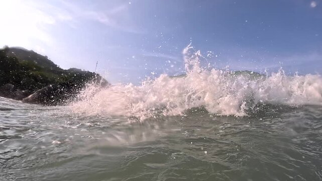 Waves crashing against rocks at a coastal location during the afternoon
