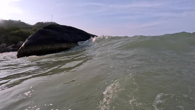 Waves crashing against rocks at the beach during sunset on a warm day