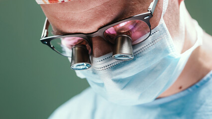 Surgeon wearing surgical mask and magnifying glasses, focused on delicate procedure in operating room, showcasing precision and professionalism in medical practice