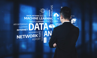 A business professional stands with arms crossed, contemplating data analytics in a modern digital workspace, showcasing technology and innovative solutions for decision-making. Tessel