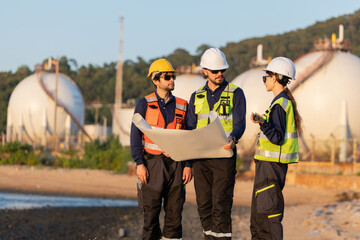 Petroleum engineers having a discussion near oil storage tanks