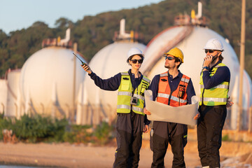 Petroleum engineers having a discussion near oil storage tanks