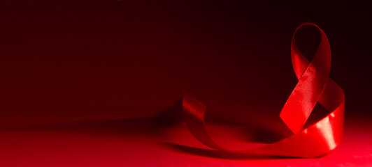 Red ribbon heart shape on red background. World Aids day concept.