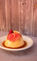 Delicioso plato de flan napolitano con fresas frescas y caramelo en una mesa de madera