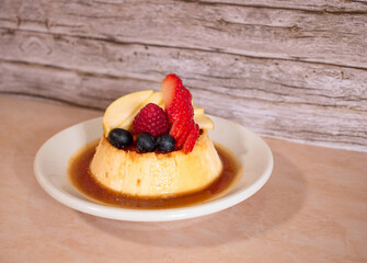 Imagen horizontal de un delicioso postre de flan napolitano con caramelo y frutos rojos
