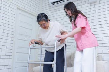 Fototapeta premium A young woman assists an elderly woman using a walker in a room