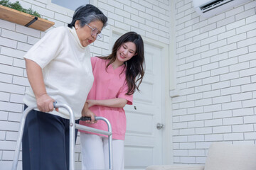 Obraz premium A young woman assists an elderly woman using a walker in a room