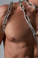 Close-up of a powerful male chest and muscular torso wrapped in a silver chain.