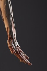 Close-up of a human arm and hand covered in dripping white plaster